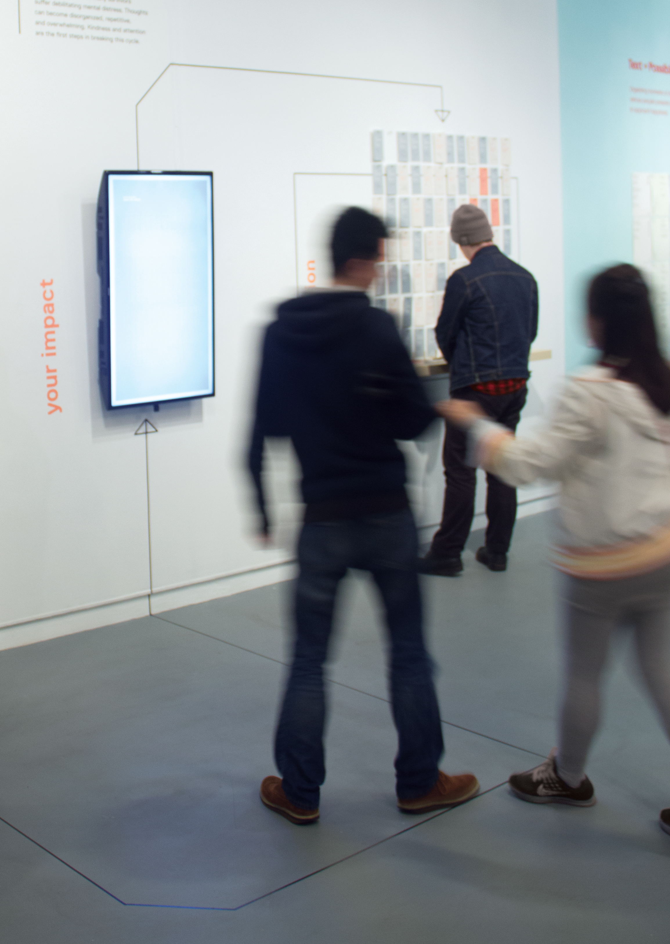 Exhibition visitors approach the interactive screen.